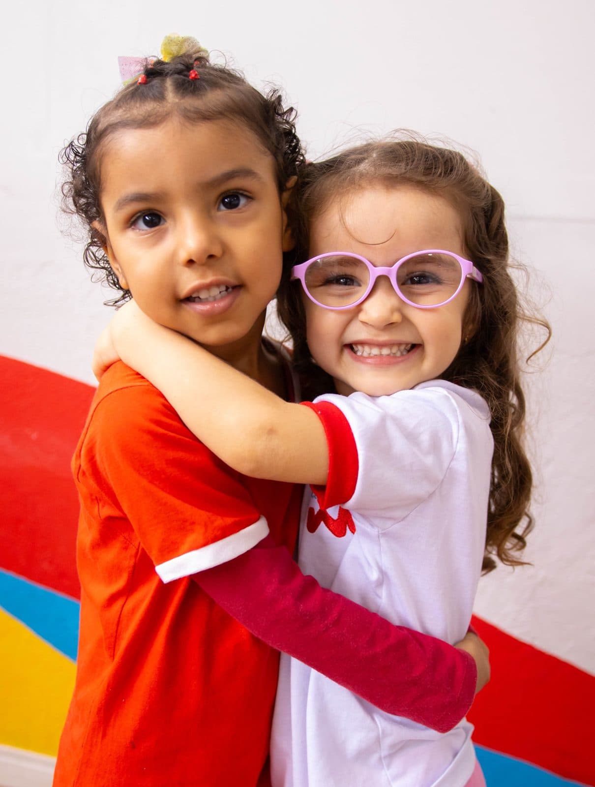 Duas alunas do Colégio We+ abraçadas e sorrindo
